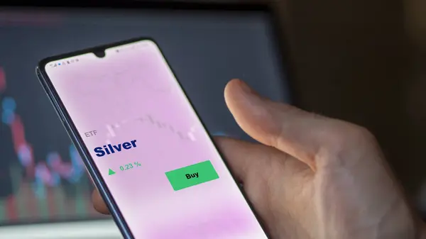 stock image An investor analyzing the silver etf fund on a screen. A phone shows the prices of Silver