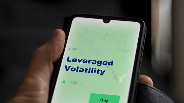 stock image An investor analyzing the leveraged volatility etf fund on a screen. A phone shows the prices of Leveraged Volatility