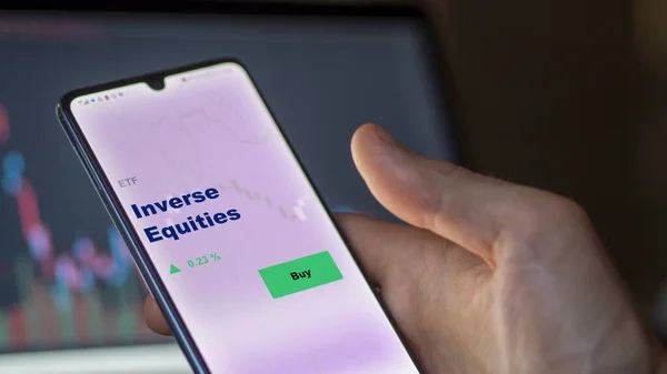 stock image An investor analyzing the inverse equities etf fund on a screen. A phone shows the prices of Inverse Equities