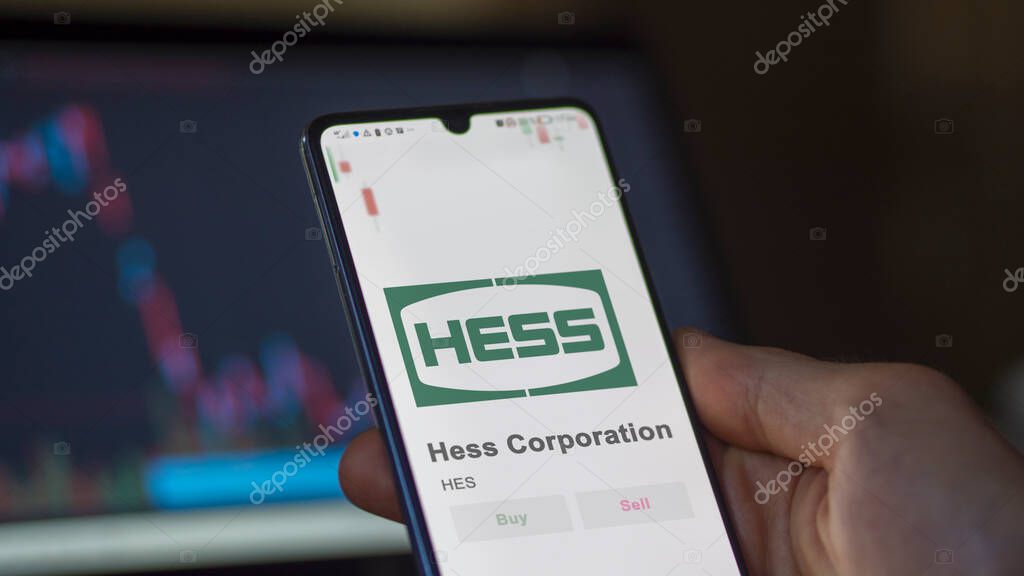 The logo of Hess Corporation on the screen of an exchange. Hess Corporation price stocks, $HES on a device.