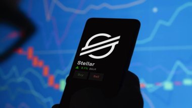 24 Kasım 2023. Bir telefondaki Stellar 'ın fiyatını analiz eden bir yatırımcı. Şifreli bir değiş tokuş için XLM dolar..