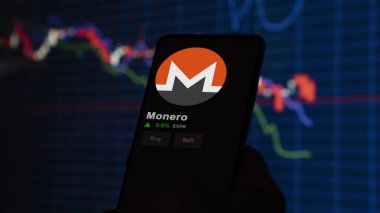24 Kasım 2023. Telefondaki Monero 'nun fiyatını analiz eden bir yatırımcı. Şifreli bir değiş tokuş için XMR dolar..