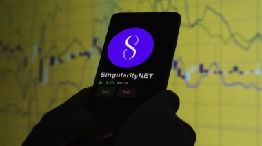24 Kasım 2023. SingularityNET 'in fiyatını telefondaki analiz eden bir yatırımcı. Kripto takası için AGIX $AGIX..