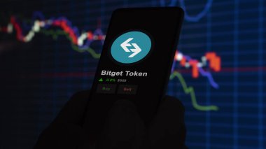 24 Kasım 2023. Telefondaki Bitget Token 'ın fiyatını analiz eden bir yatırımcı. Kripto değiş tokuşunda BGB' ye ait bozuk para..