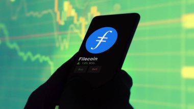24 Kasım 2023. Telefondaki filecoin 'in fiyatını analiz eden bir yatırımcı. Kripto takası için FIL dolar..