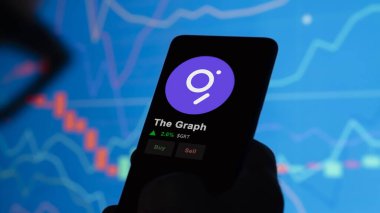 24 Kasım 2023. Telefondaki Grafik 'in fiyatını analiz eden bir yatırımcı. Kripto değiş tokuşunda GRT $' lık bozuk para..