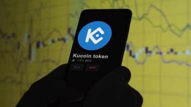 24 Kasım 2023. Telefondaki kucoin jetonunun fiyatını analiz eden bir yatırımcı. Kripto değiş tokuşunda KCS $KCS..