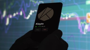 24 Kasım 2023. Telefondaki Klaytn 'ın fiyatını analiz eden bir yatırımcı. Kripto takası için KLAY $KLAY..