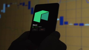 24 Kasım 2023. Telefondaki Neo 'nun fiyatını analiz eden bir yatırımcı. Şifreli bir değiş tokuş için NEO $..