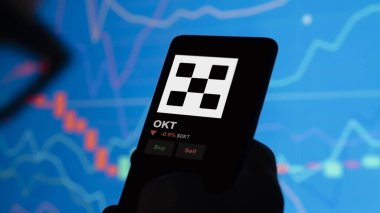 24 Kasım 2023. Bir telefondaki OKT 'nin fiyatını analiz eden bir yatırımcı. Kripto değiş tokuşunda bozuk para..