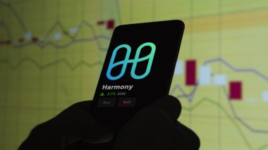 24 Kasım 2023. Telefondaki Harmony 'nin fiyatını analiz eden bir yatırımcı. Kripto değiş tokuşunda 1 dolarlık bozuk para..