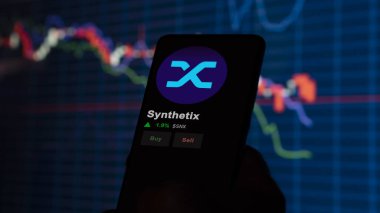 24 Kasım 2023. Telefondaki Sentetik 'in fiyatını analiz eden bir yatırımcı. Şifreli bir değiş tokuş için SNX dolar..