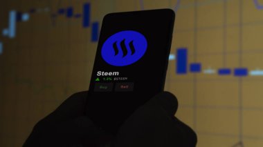 24 Kasım 2023. Telefondaki Steem 'in fiyatını analiz eden bir yatırımcı. Kripto değiş tokuşunda STEEM $' lık bozuk para..