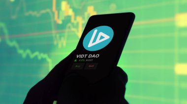 24 Kasım 2023. Telefondaki VIDT DAO 'nun fiyatını analiz eden bir yatırımcı. Kripto değiş tokuşunda VIDT $VIDT..