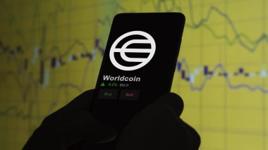 24 Kasım 2023. Bir telefondaki Worldcoin 'in fiyatını analiz eden bir yatırımcı. Şifreli bir değiş tokuş için WLD $..