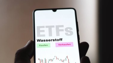 Aralık 2022. Bir yatırımcı telefon ekranındaki hidrojen ETF fonunu Wasserstoff-ETF 'lerde analiz eder. Almanca metin: Kaufen, Verkaufen, Wasserstoff satın al, sat, hidrojen