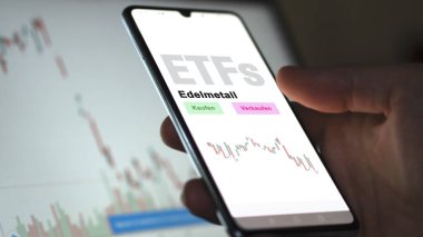 Aralık 2022. Bir yatırımcı, telefon ekranı Edelmetall-ETF 'deki değerli metal ETF fonunu analiz eder. Almanca çeviri: Kaufen, Verkaufen, Edelmetall al-sat, değerli metal