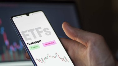 Aralık 2022. Bir yatırımcı, telefon ekranı Rohstoff-ETF 'deki hammadde ETF fonunu analiz eder. Almanca metin: Kaufen, Verkaufen, Rohstoff alım-satım, ham madde