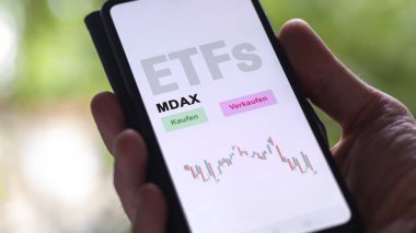 Aralık 2022. Bir yatırımcı MDAX ETF fonunu telefon ekranı MDAX-ETF 'lerde analiz eder. Almanca çeviri: Kaufen, Verkaufen: al, sat