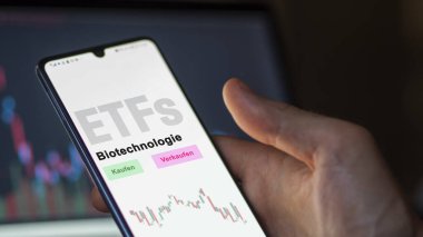 Aralık 2022. Bir yatırımcı biyoteknoloji ETF fonunu telefon ekranındaki biyoteknoloji-ETF 'lerde analiz eder. Almanca metin: Kaufen, Verkaufen, Biotechnologie satın al, sat, biyoteknoloji