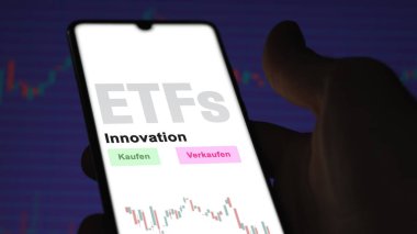 Aralık 2022. Bir yatırımcı, telefon ekranı Innovation-ETF 'lerdeki yenilikçi ETF fonunu analiz eder. Almanca çeviri: Kaufen, Verkaufen: al, sat