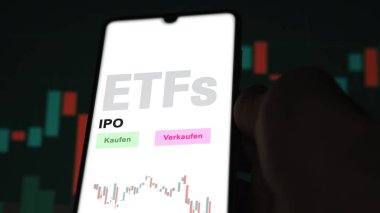 Aralık 2022. Bir yatırımcı telefon ekranında halka arz edilen ETF fonunu analiz eder. Almanca çeviri: Kaufen, Verkaufen: al, sat