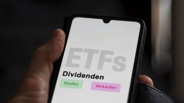 Aralık 2022. Bir yatırımcı ETF fonunu telefon ekranında analiz eder Dividenden-ETF 'lerde. Almanca metin: Kaufen, Verkaufen, Dividenden al, sat, kar payları