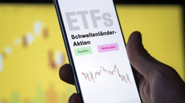 Aralık 2022. Bir yatırımcı telefon ekranı Schwellenlander-Aktien-ETF 'lerde yükselen piyasa ETF fonunu analiz eder. Almanca metin: Kaufen, Verkaufen, Schwellenlander-Aktien Alış, Satış, Gelişmekte Olan Piyasa Varlıkları