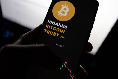 Bir el, Bitcoin Güven ETF 'yi Bitcoin sembolü ve yatırım grafiği ile gösteren akıllı telefonu tutuyor.