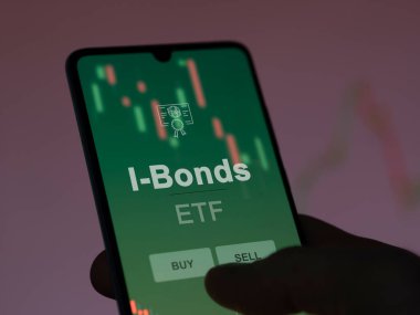 Ekrandaki i-bonoları analiz eden bir yatırımcı. Bir telefon I-Bonds fiyatlarını gösterir