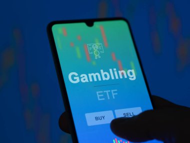 Kumarhane fonunu ekranda analiz eden bir yatırımcı. Kumar fiyatlarını gösteren bir telefon.