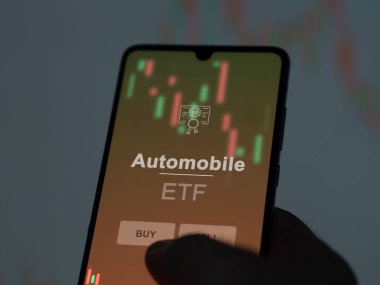 Otomobil fonunu ekranda analiz eden bir yatırımcı. Otomobil fiyatlarını gösteren bir telefon