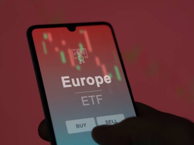 Ekranda Avrupa ETF fonunu analiz eden bir yatırımcı. Avrupa 'nın fiyatlarını gösteren bir telefon