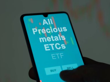 An investor analyzing the all precious metals etcs etf fund on a screen. A phone shows the prices of All Precious metals ETCs clipart