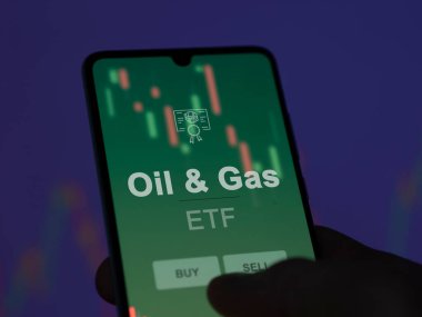 Ekranda petrol ve doğalgaz fonunu analiz eden bir yatırımcı. Bir telefon Petrol & Benzin fiyatlarını gösterir