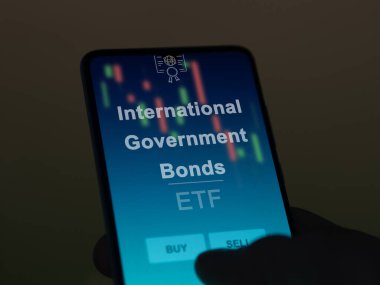 Ekranda uluslararası devlet tahvilleri fonunu analiz eden bir yatırımcı. Uluslararası hükümet bonolarının fiyatlarını gösteren bir telefon