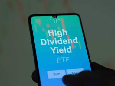 Yüksek kar payını analiz eden bir yatırımcı bir ekranda etf fonu veriyor. Bir telefon, Yüksek Bölünme Verimliliği 'nin fiyatlarını gösterir