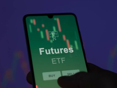 Bir yatırımcı ekrandaki fonları analiz ediyor. Bir telefon Geleceğin fiyatlarını gösterir