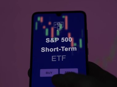 S & p 500 kısa vadeli etf fonunu ekranda analiz eden bir yatırımcı. S & P 500 kısa dönem fiyatlarını gösteren bir telefon