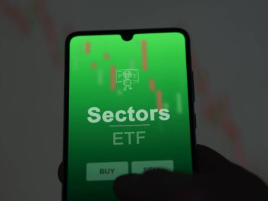 Bir yatırımcı ekranda sektör fonlarını analiz ediyor. Sektörlerin fiyatlarını gösteren bir telefon