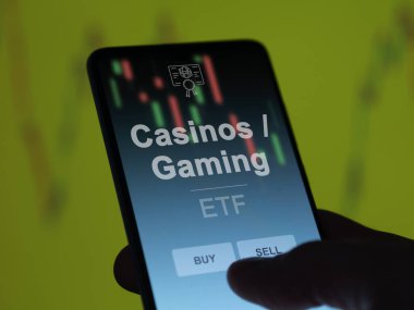 Bir yatırımcı ekranda kumarhaneleri ve oyun fonlarını analiz ediyor. Bir telefon kumarhanelerin / kumarhanelerin fiyatlarını gösterir