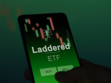 Bir yatırımcı, ekrandaki basamaklı ETF fonunu analiz ediyor. Bir telefon Merdiven fiyatlarını gösterir
