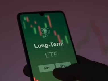Ekranda uzun vadeli etf fonunu analiz eden bir yatırımcı. Bir telefon uzun vadeli fiyatları gösterir
