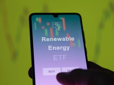 Ekranda yenilenebilir enerji etf fonunu analiz eden bir yatırımcı. Bir telefon yenilenebilir enerji fiyatlarını gösterir