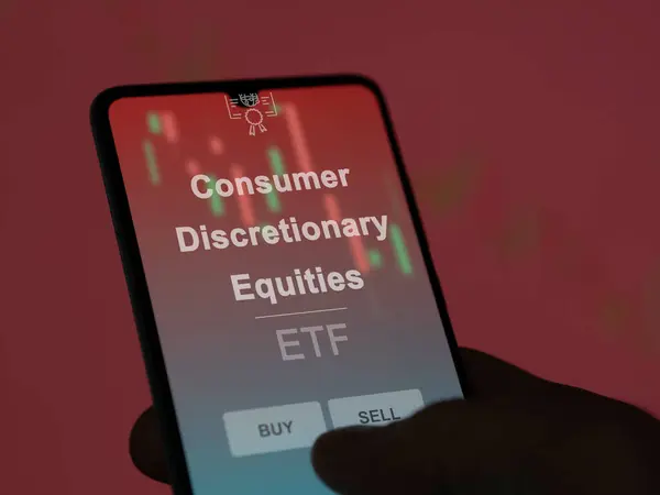 stock image An investor analyzing the consumer discretionary equities etf fund on a screen. A phone shows the prices of Consumer Discretionary Equities