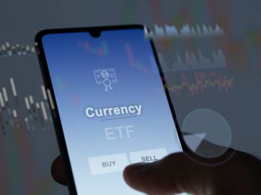 Ekranda para birimini analiz eden bir yatırımcı. Bir telefon para biriminin fiyatlarını gösterir