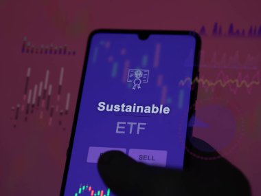 Bir yatırımcı ekrandaki sürdürülebilir etf fonunu analiz ediyor. Bir telefon sürdürülebilir fiyatları gösterir
