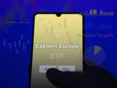 Doğu Avrupa etf fonunu ekranda analiz eden bir yatırımcı. Doğu Avrupa 'nın fiyatlarını gösteren bir telefon