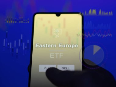 An investor analyzing the eastern europe etf fund on a screen. A phone shows the prices of Eastern Europe clipart