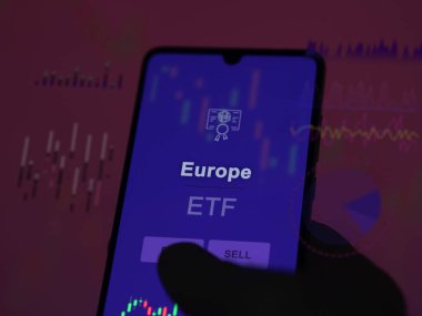 Ekranda Avrupa ETF fonunu analiz eden bir yatırımcı. Avrupa 'nın fiyatlarını gösteren bir telefon